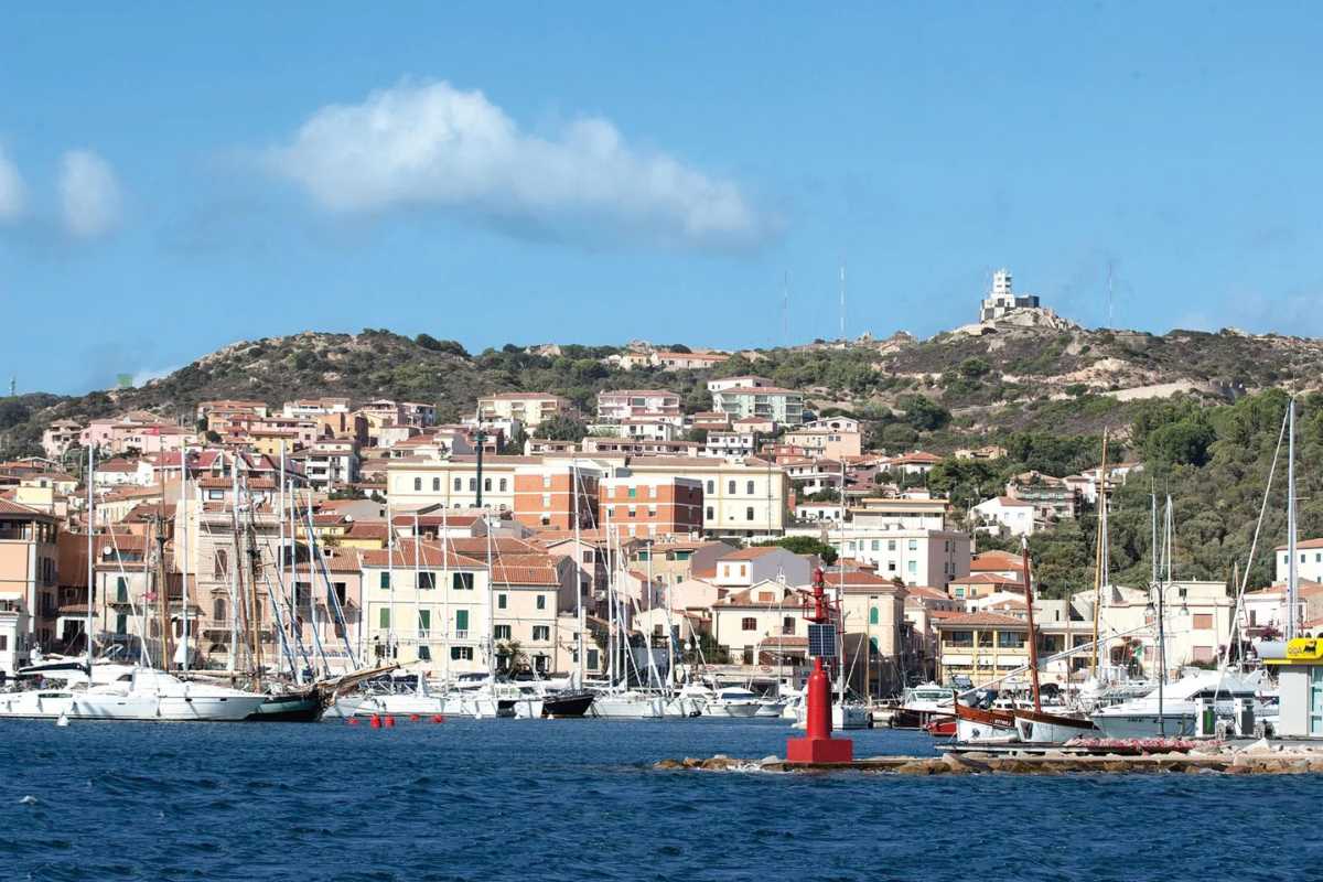 Vista panoramica dall’alto dell’arcipelago di La Maddalena con mare turchese, barche ormeggiate e il centro storico di La Maddalena sullo sfondo